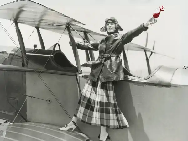aviatrix on biplane with glass of red wine